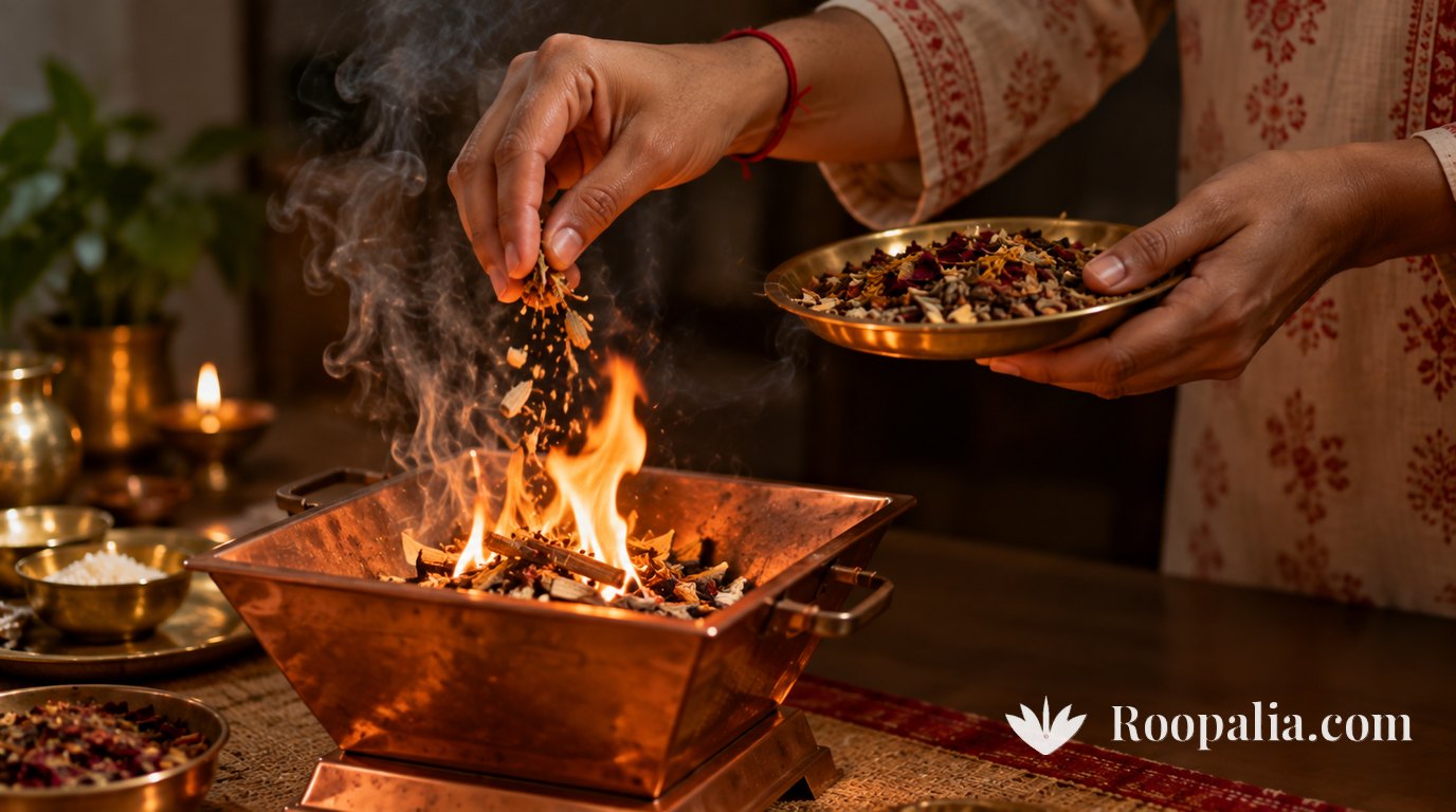 Hands in a cotton kurta releasing a pinch of dry offering mixture into a small copper havan kund with a low flame, a red thread on the right wrist and a brass plate held in the other hand — AI-generated image (Roopalia)