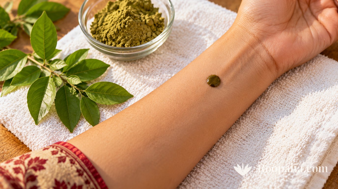 A single dot of henna paste on the inner wrist as a patch test, with fresh henna leaves and powder nearby.