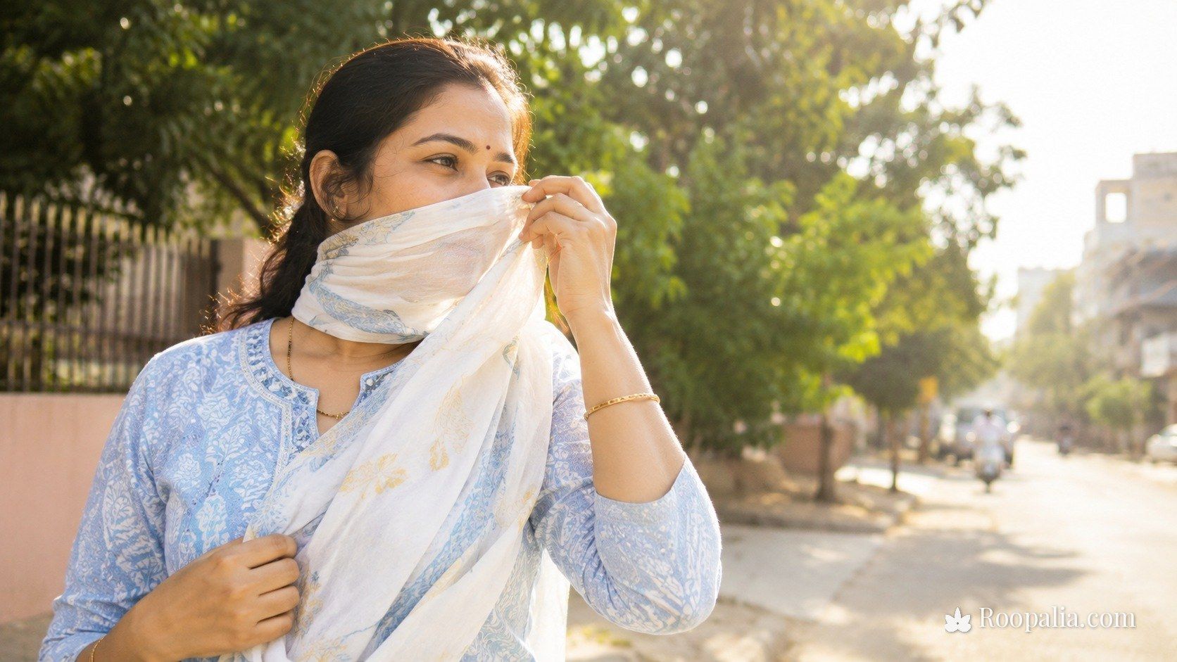 Sun protection for pigmentation — a woman shielding her face from bright sunlight with a light scarf